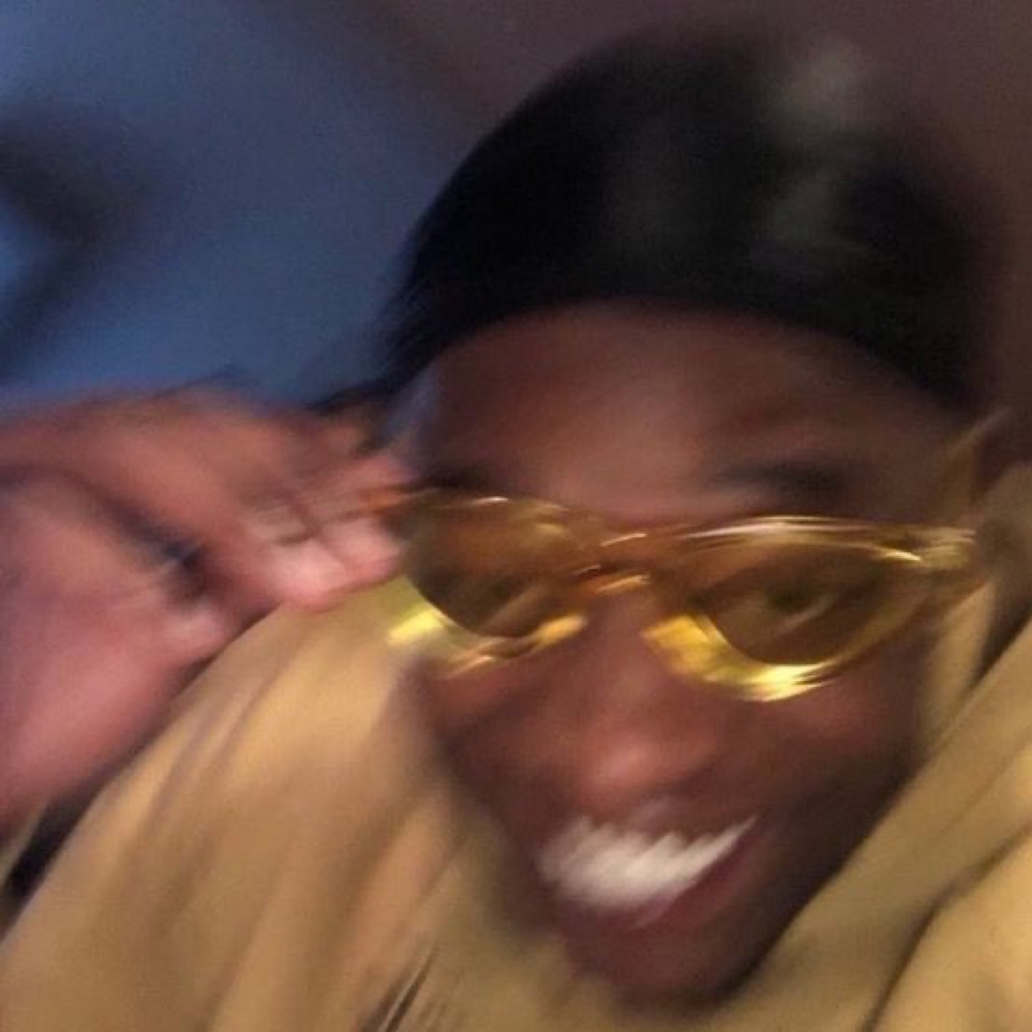 Blurry selfie of a man lowering tinted glasses with a cheeky grin