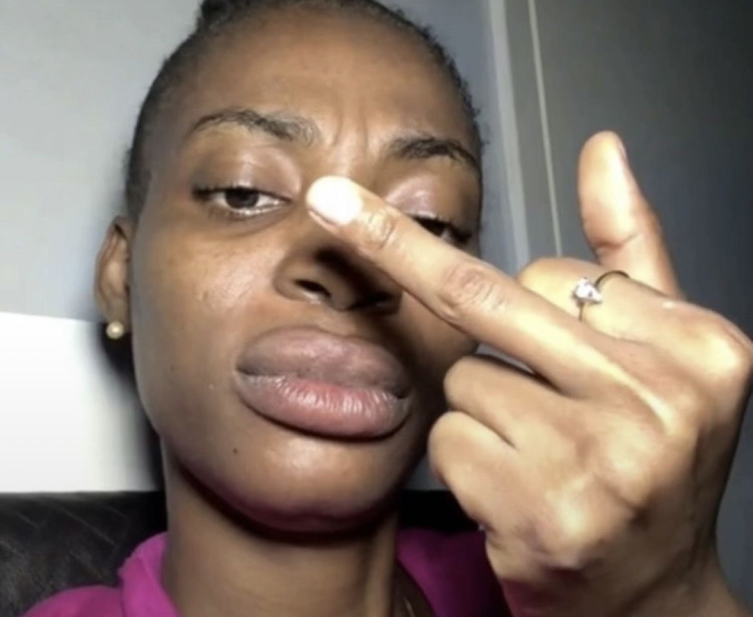 Woman with a flat, exhausted face raising her middle finger toward the camera