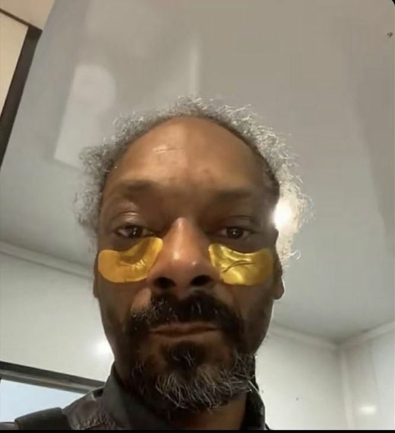 Snoop Dogg selfie in gold under-eye patches wearing a completely deadpan face