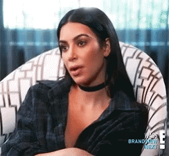 Woman in a plaid top talking flatly to the camera with a cool, unbothered expression