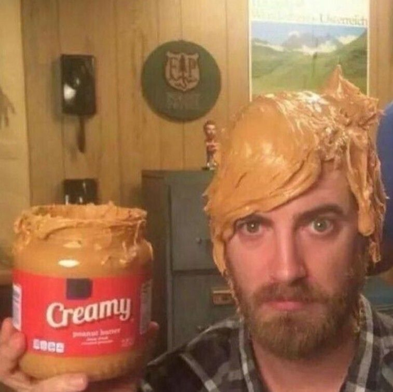 Guy with peanut butter smeared on his head holding a Creamy jar with an utterly deadpan stare