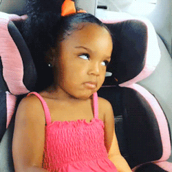 Toddler girl in a pink car seat giving the most over-it side-eye imaginable