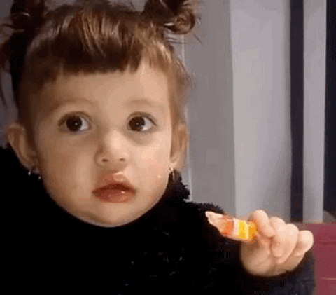 Toddler clutching a piece of candy and staring dead-eyed at the camera