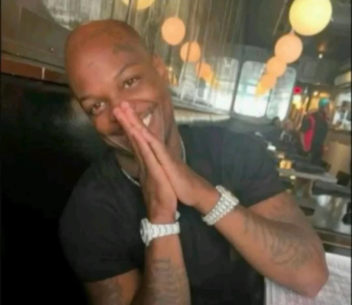 Bald tattooed man grinning with hands pressed together, looking extremely pleased with himself