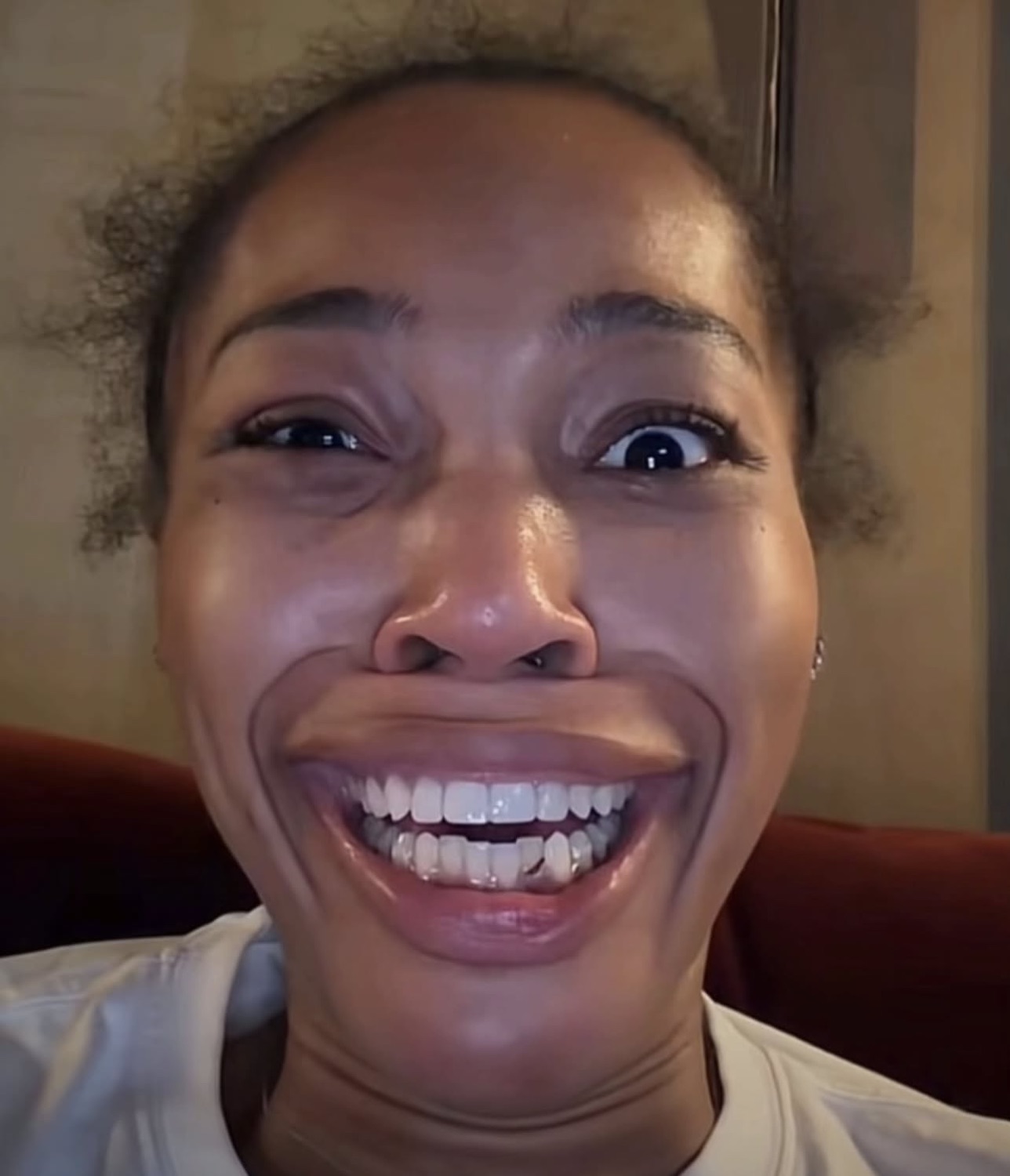 Extreme close-up of Quenlin Blackwell with a hugely exaggerated, stretched wide grin showing all her teeth
