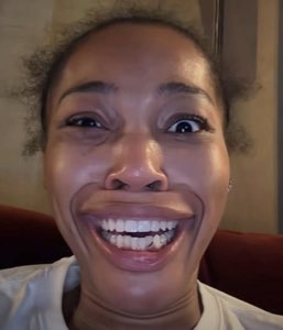 Extreme close-up of Quenlin Blackwell with a hugely exaggerated, stretched wide grin showing all her teeth