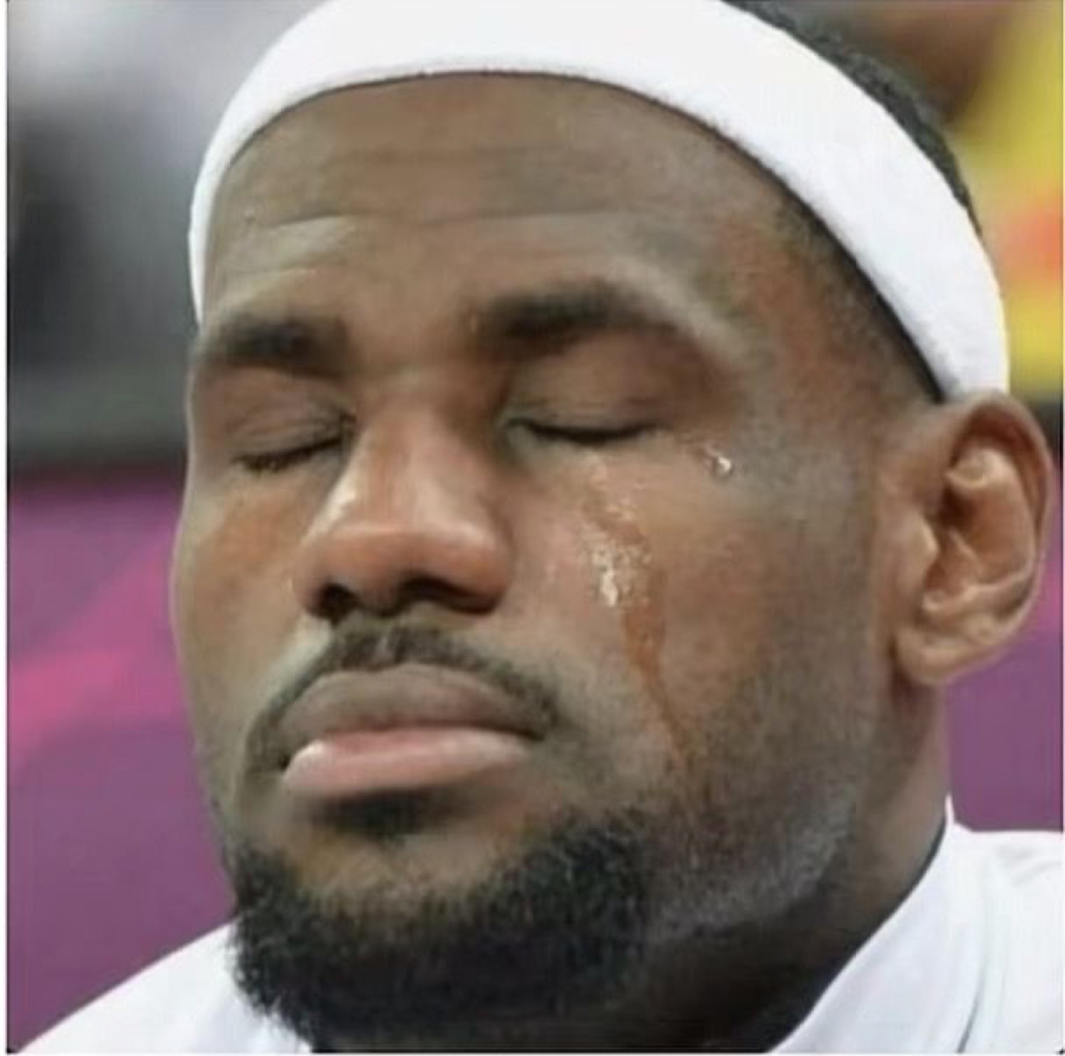 Basketball player in a headband with eyes closed and a single tear rolling down his cheek