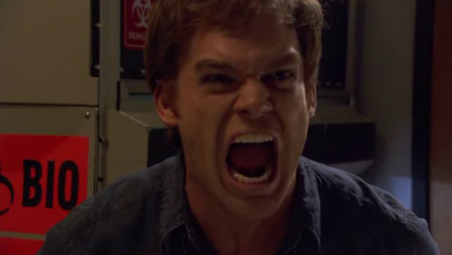 Man screaming with full-on rage in front of a red BIO sign