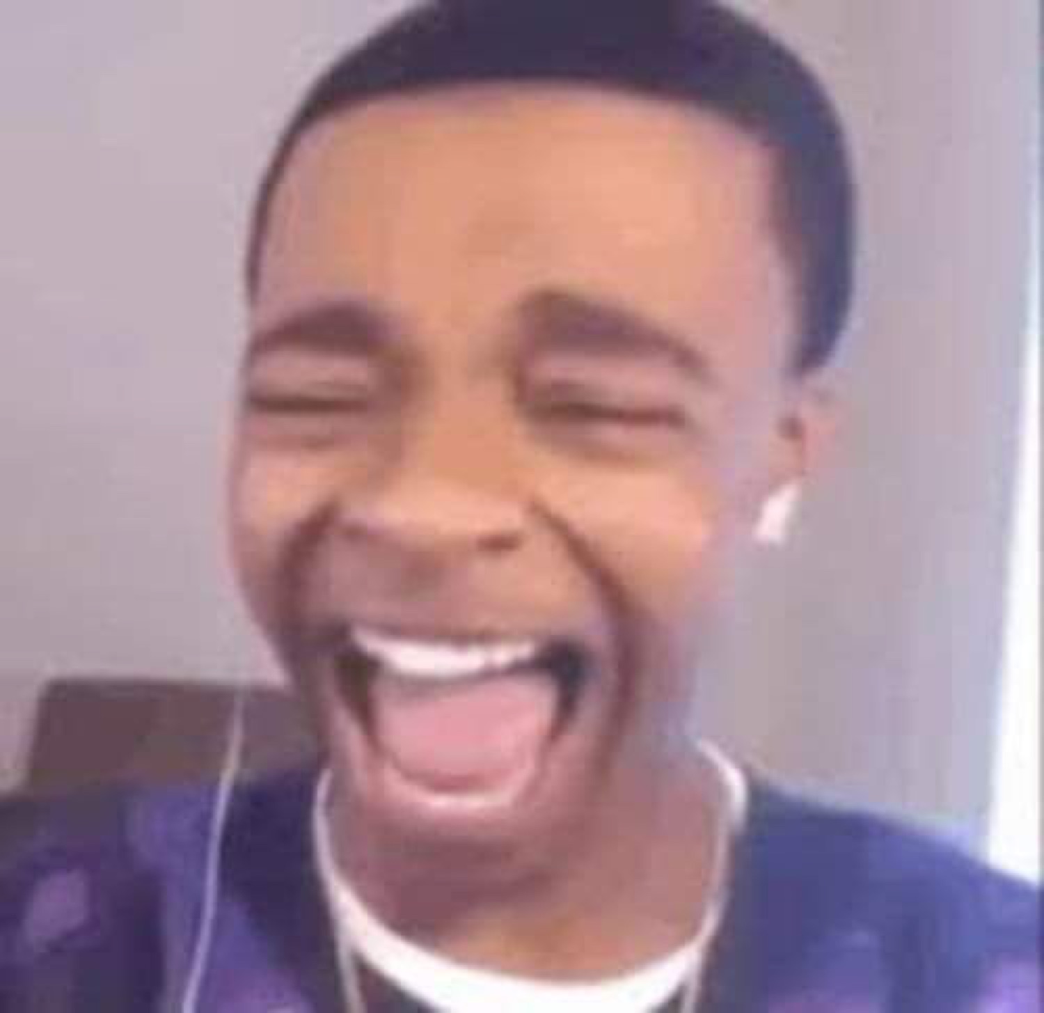 Young man absolutely losing it laughing with eyes shut and mouth wide open