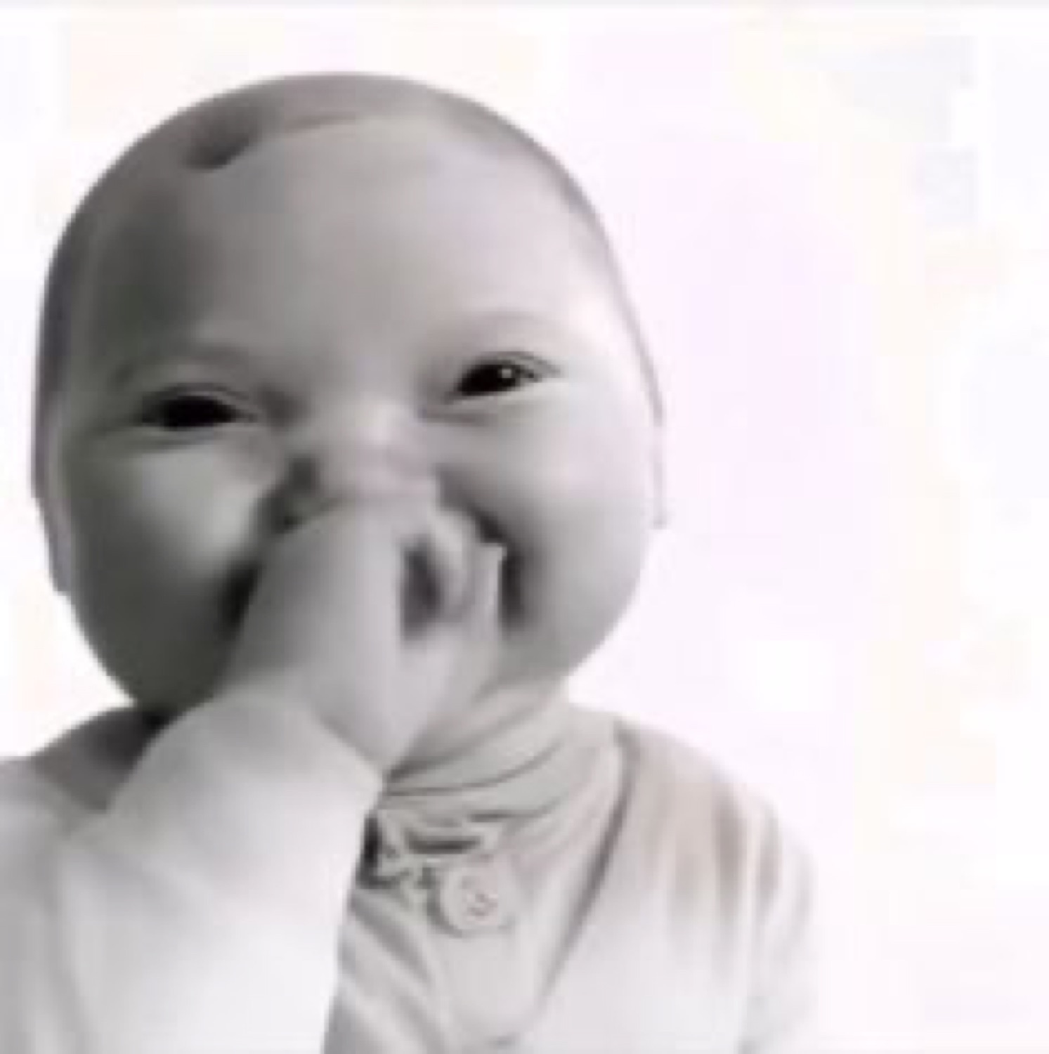 Baby covering its mouth with a hand, stifling a shy, embarrassed giggle