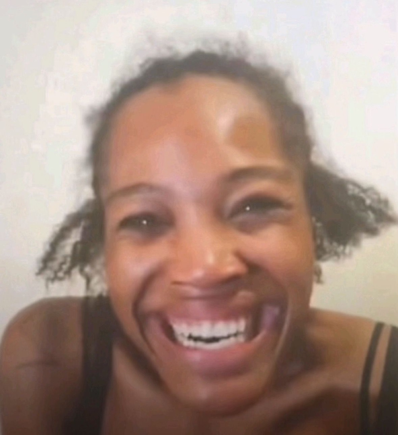 Woman on a video call cracking up with a huge open-mouthed laugh