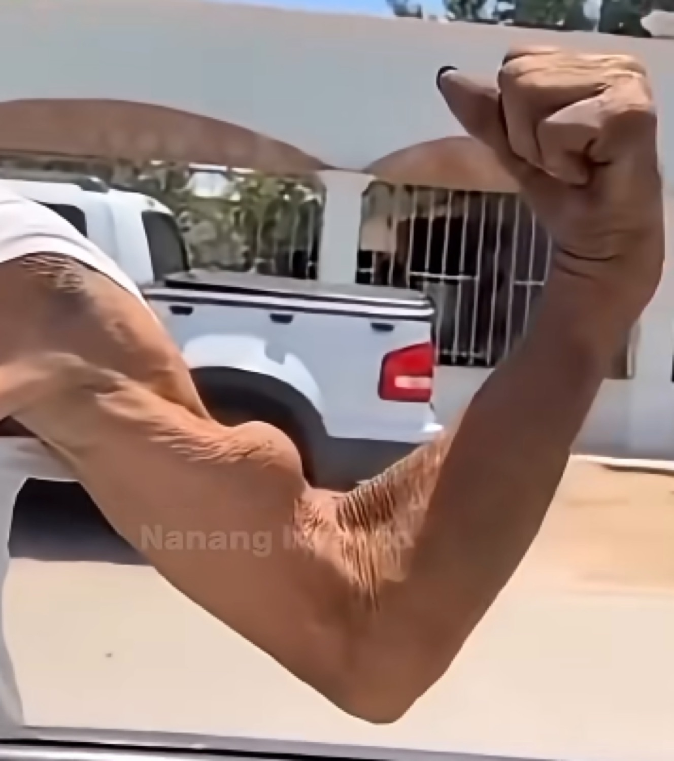 Close-up of a flexed arm resting on a car window