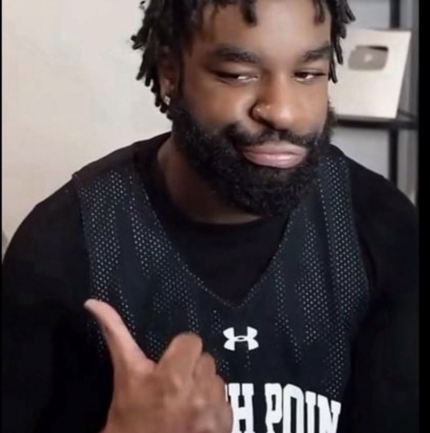 Bearded man smirking and pointing a thumb back at himself