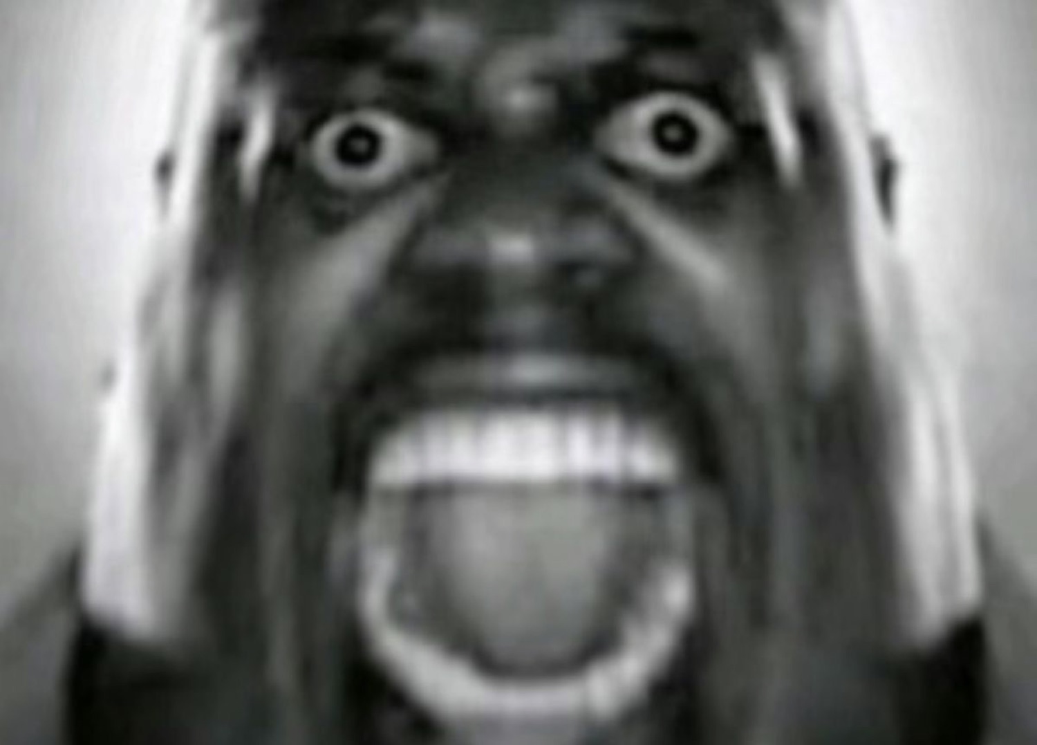 Grainy black-and-white close-up of a man screaming with wide bulging eyes