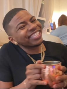 Man in a black tee grinning ear to ear while holding a copper mug