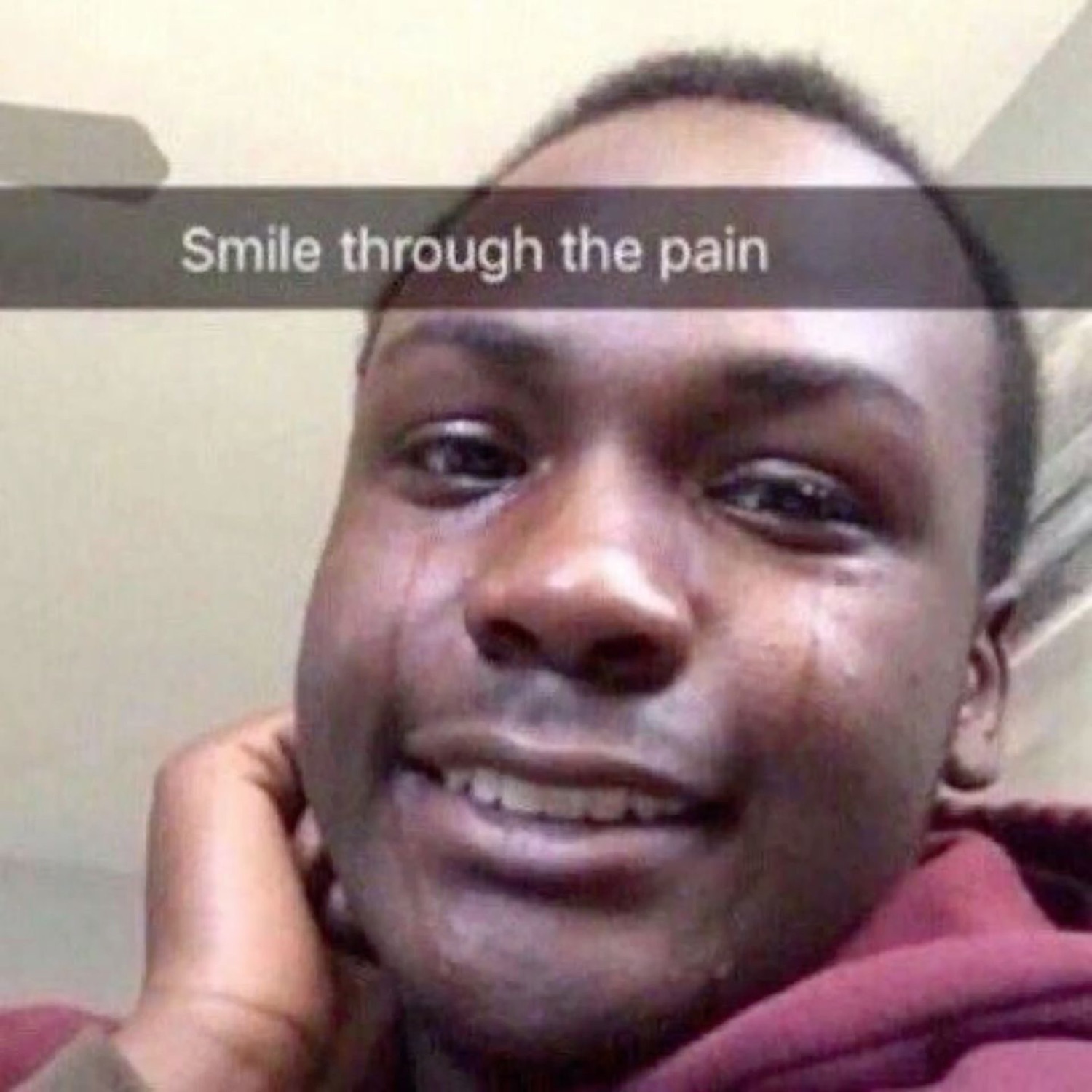 Teary young man forcing a smile, captioned 'Smile through the pain'