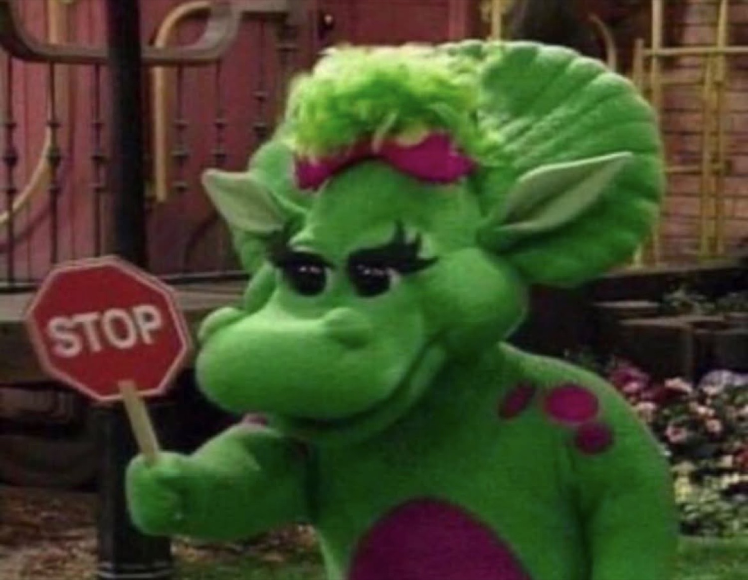 Baby Bop from Barney holding up a STOP sign