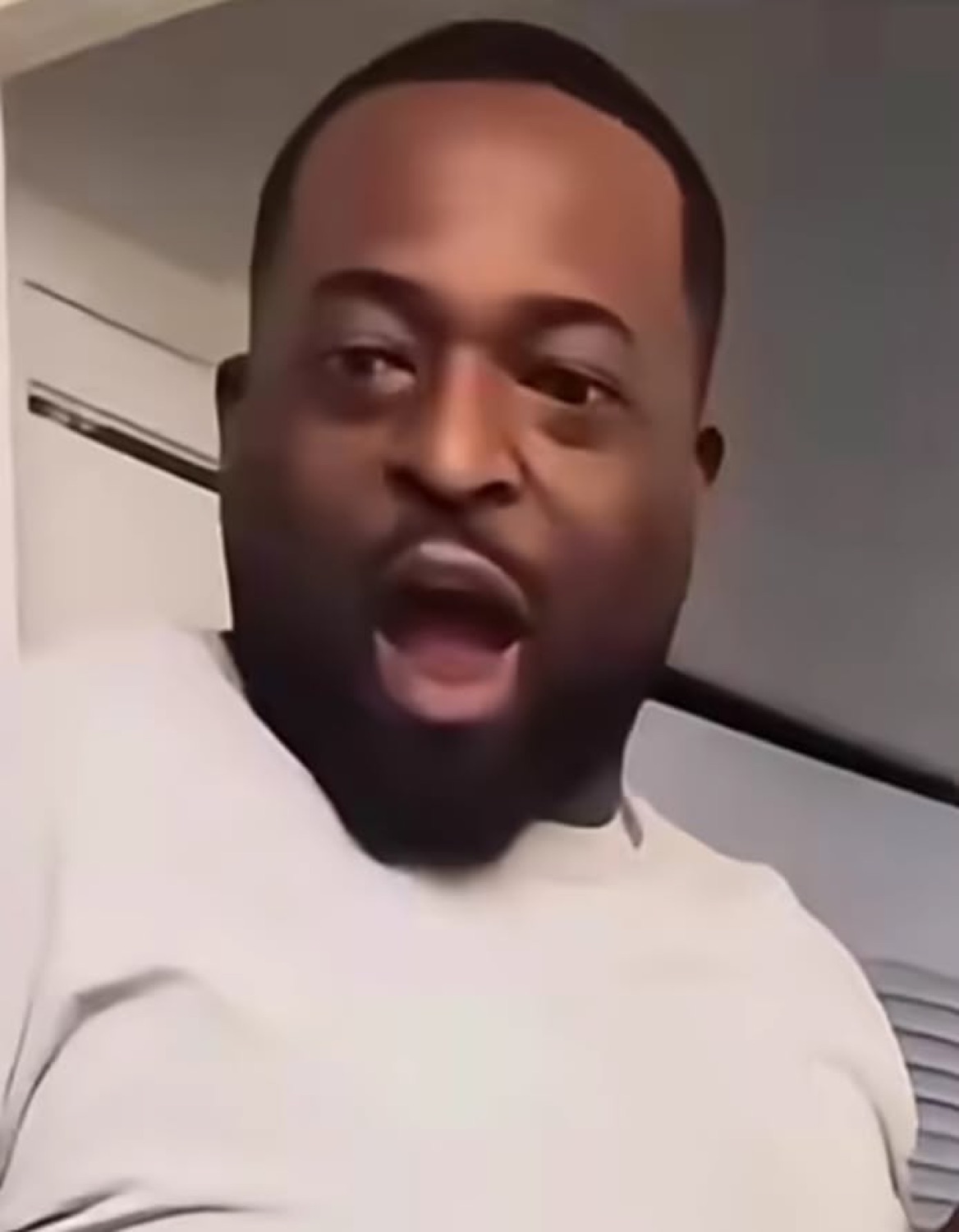 Bearded man in white shirt with mouth wide open mid-exclamation