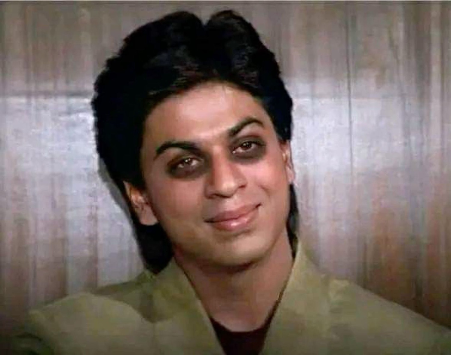 Young Shah Rukh Khan with smudged dark eyes giving a sly smile