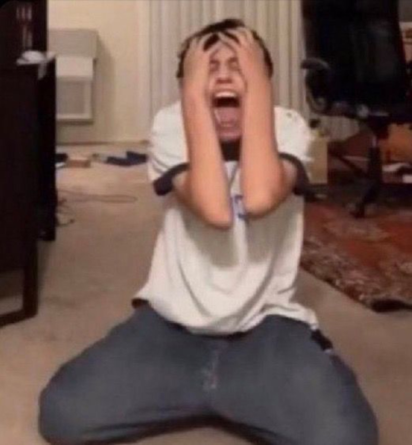 Man on his knees clutching his head and screaming in anguish