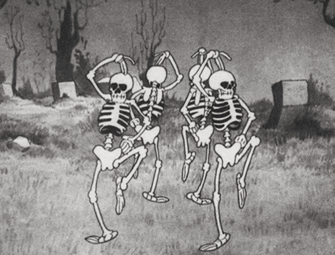 Black and white cartoon skeletons dancing in a graveyard