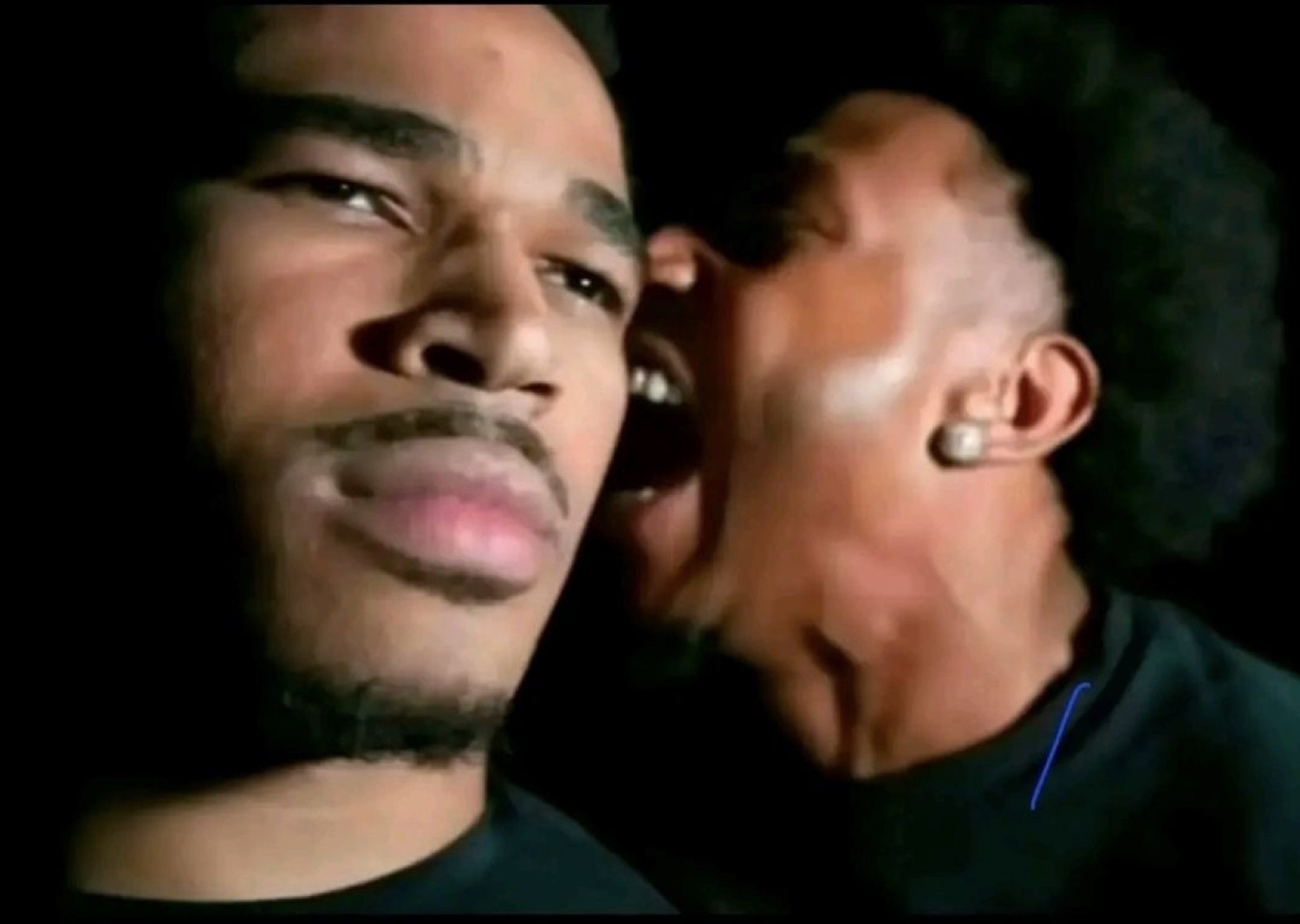 Man yelling right into a calm man's ear