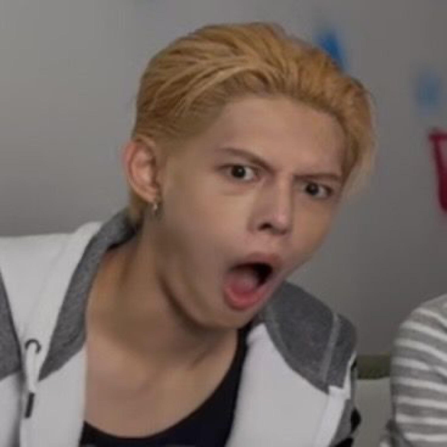 Young man with blond hair and wide-open mouth reacting in total shock, eyes wide
