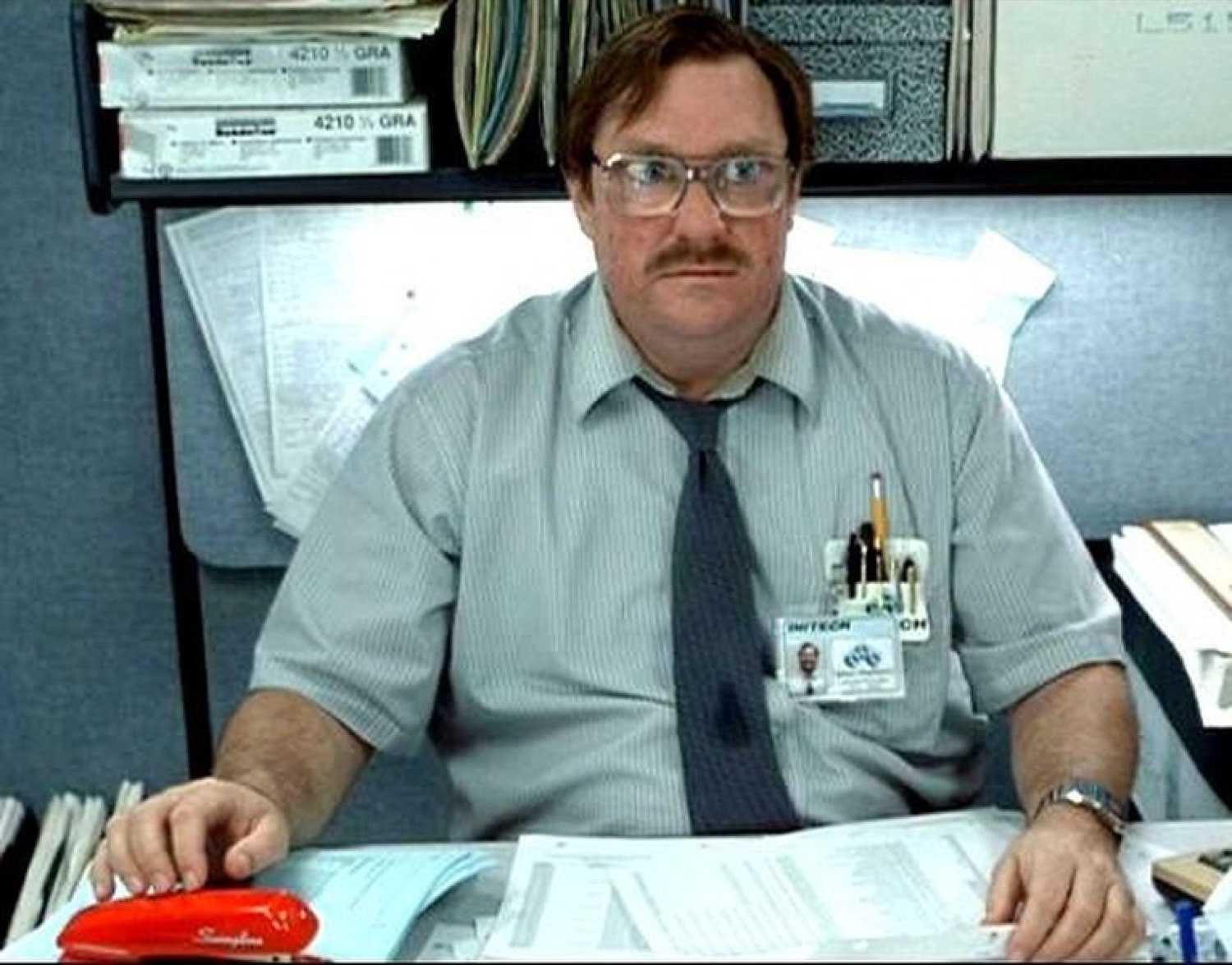 Office Space's Milton sitting at his cluttered cubicle, staring blankly with zero enthusiasm