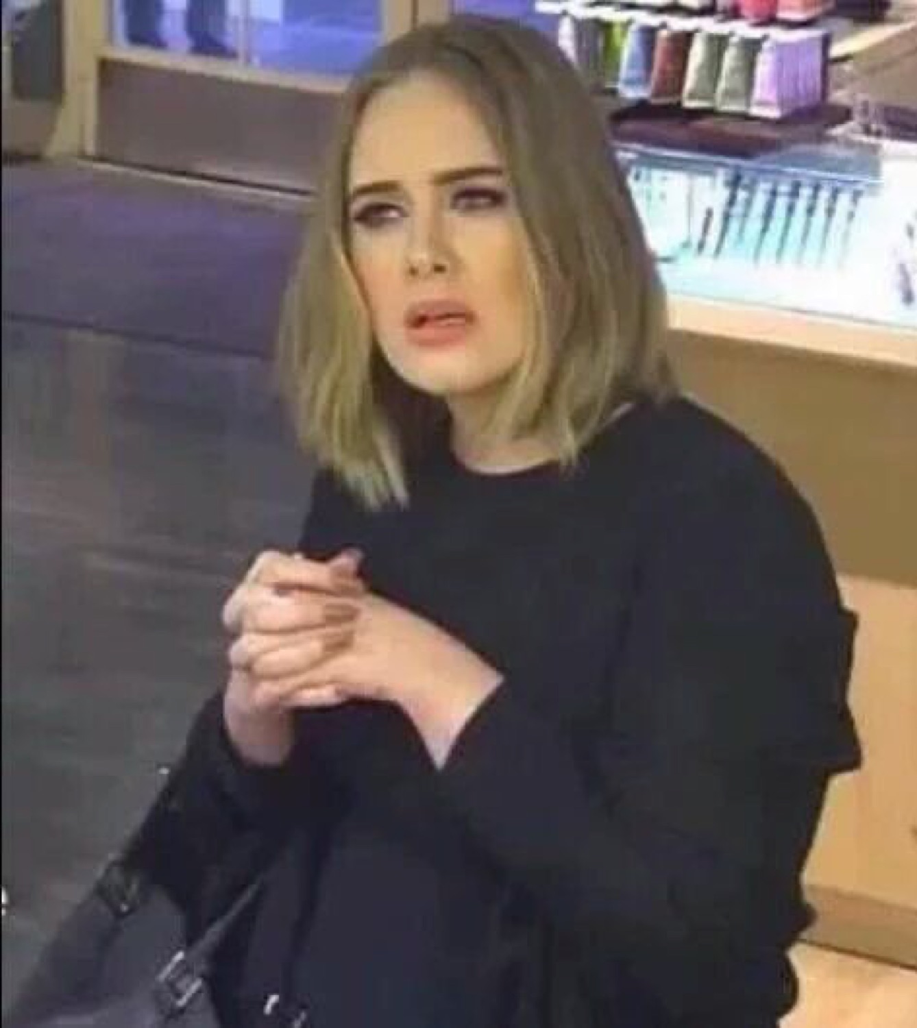 Woman in a shop wringing her hands with a confused, uneasy expression