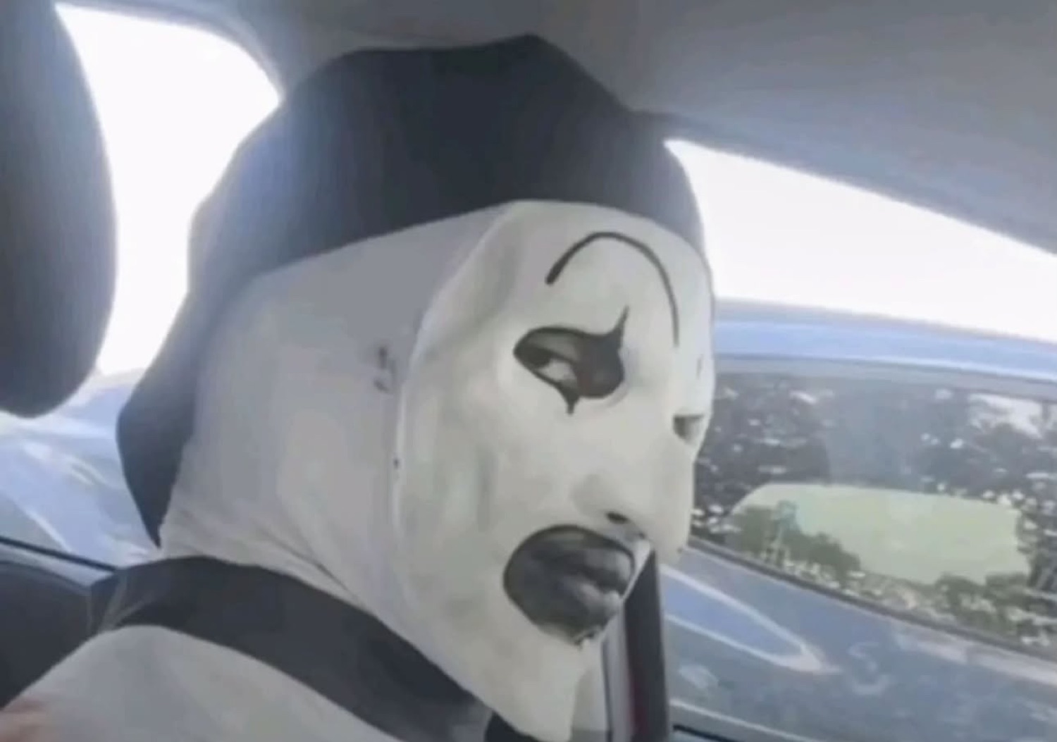 Art the Clown in a car seat staring blankly out the window looking utterly unbothered