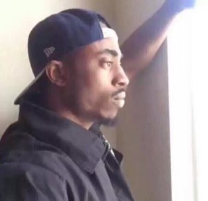 Young man in a backwards cap gazing sideways out of a window with a deeply contemplative look