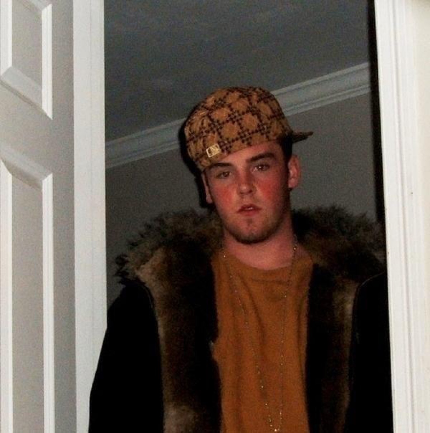Scumbag Steve in a sideways fur-lined hat leaning in a doorway with a smug stare