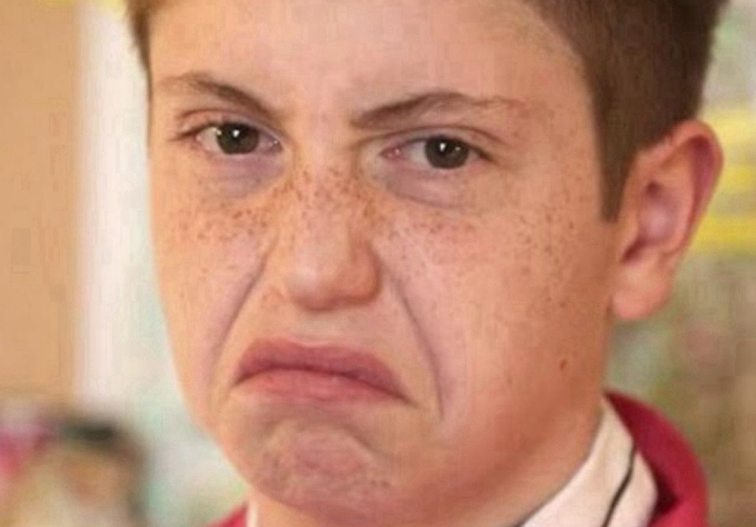 Freckled kid with an exaggerated frowning grimace of disgust