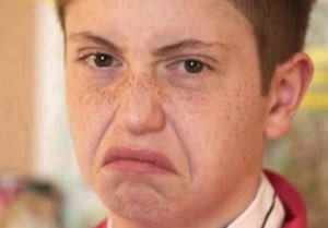 Freckled kid with an exaggerated frowning grimace of disgust