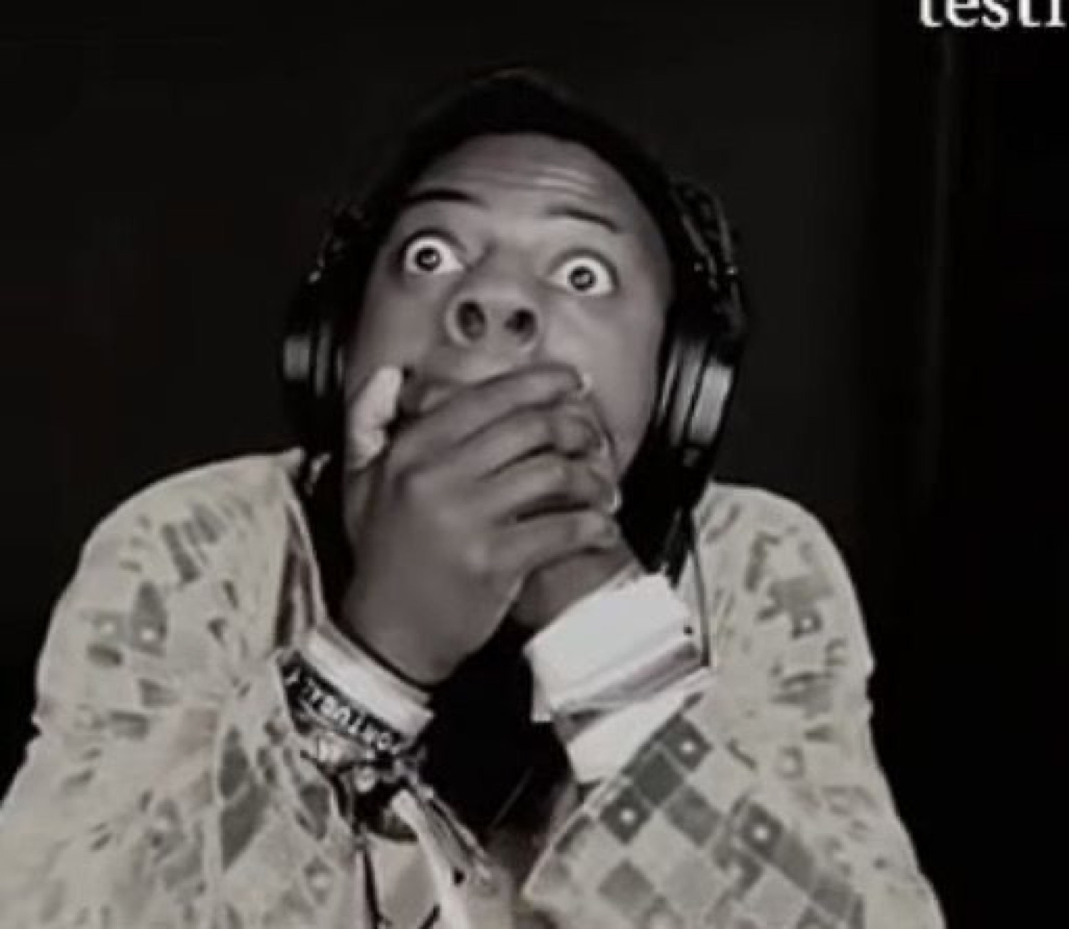 Man in headphones with bulging eyes covering his mouth in total shock