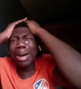 Person in an orange shirt clutching their head and sobbing dramatically