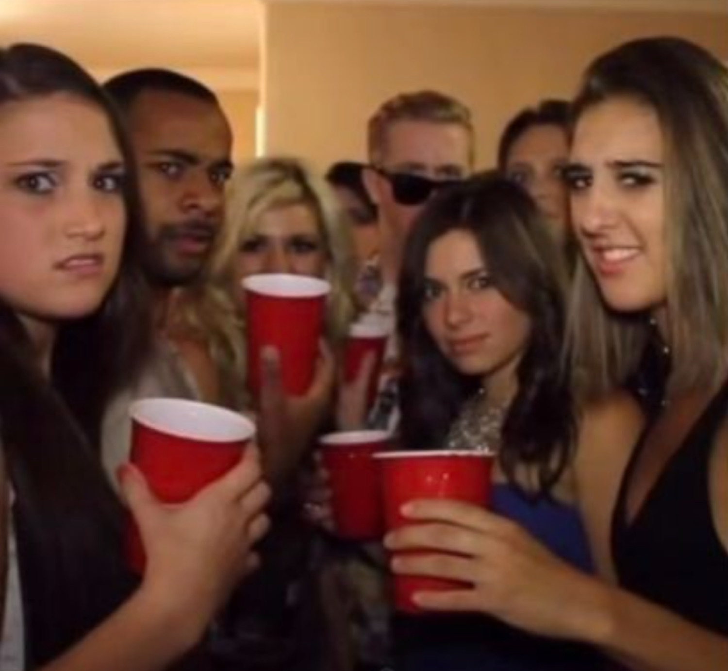 Cramped house party crowd with red cups giving side-eye and uneasy stares at the camera