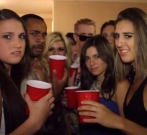 Cramped house party crowd with red cups giving side-eye and uneasy stares at the camera