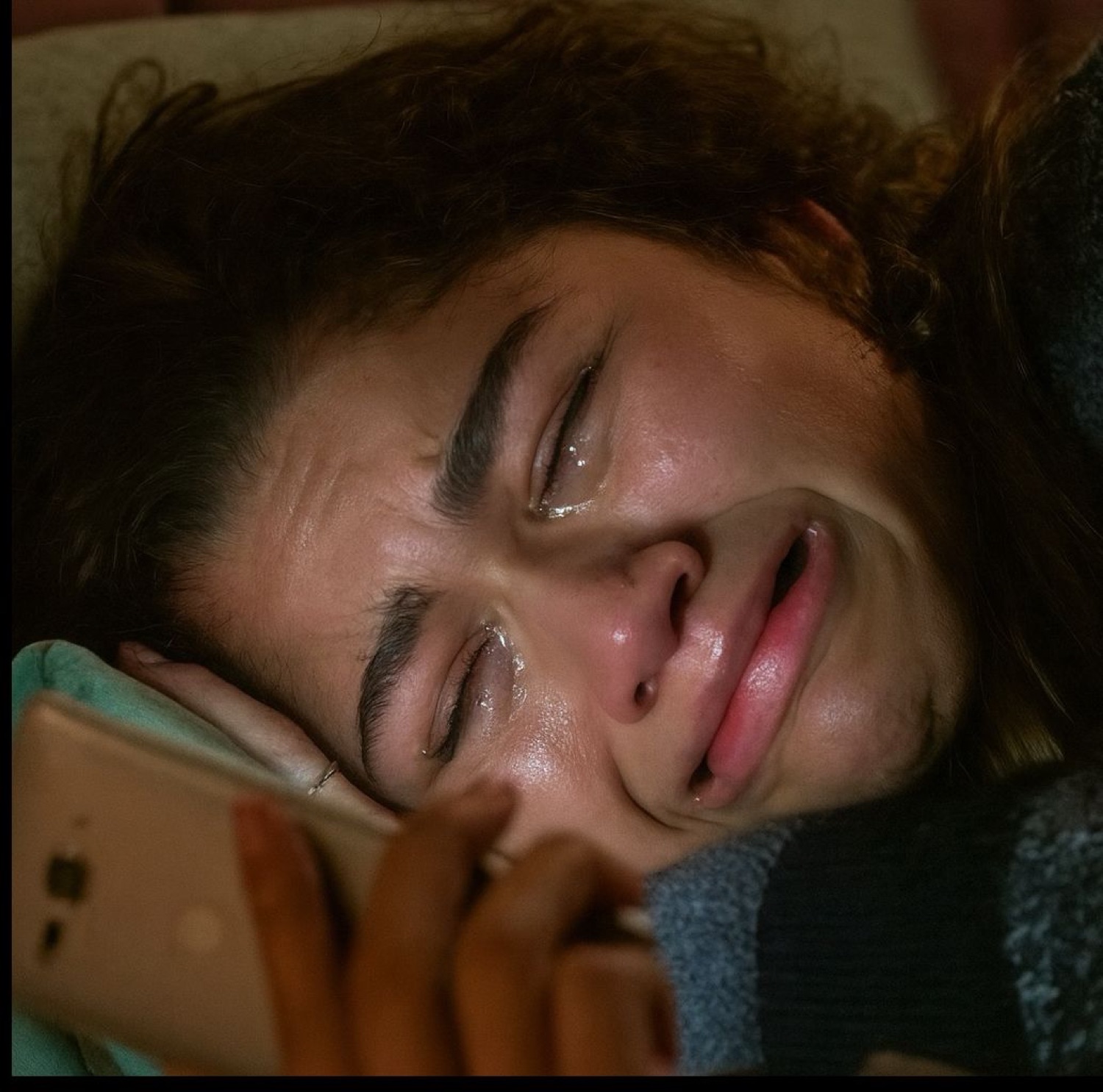 Person lying down crying on the phone, tears streaming down their face