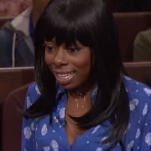 Woman on a talk show with a stiff, awkward forced smile