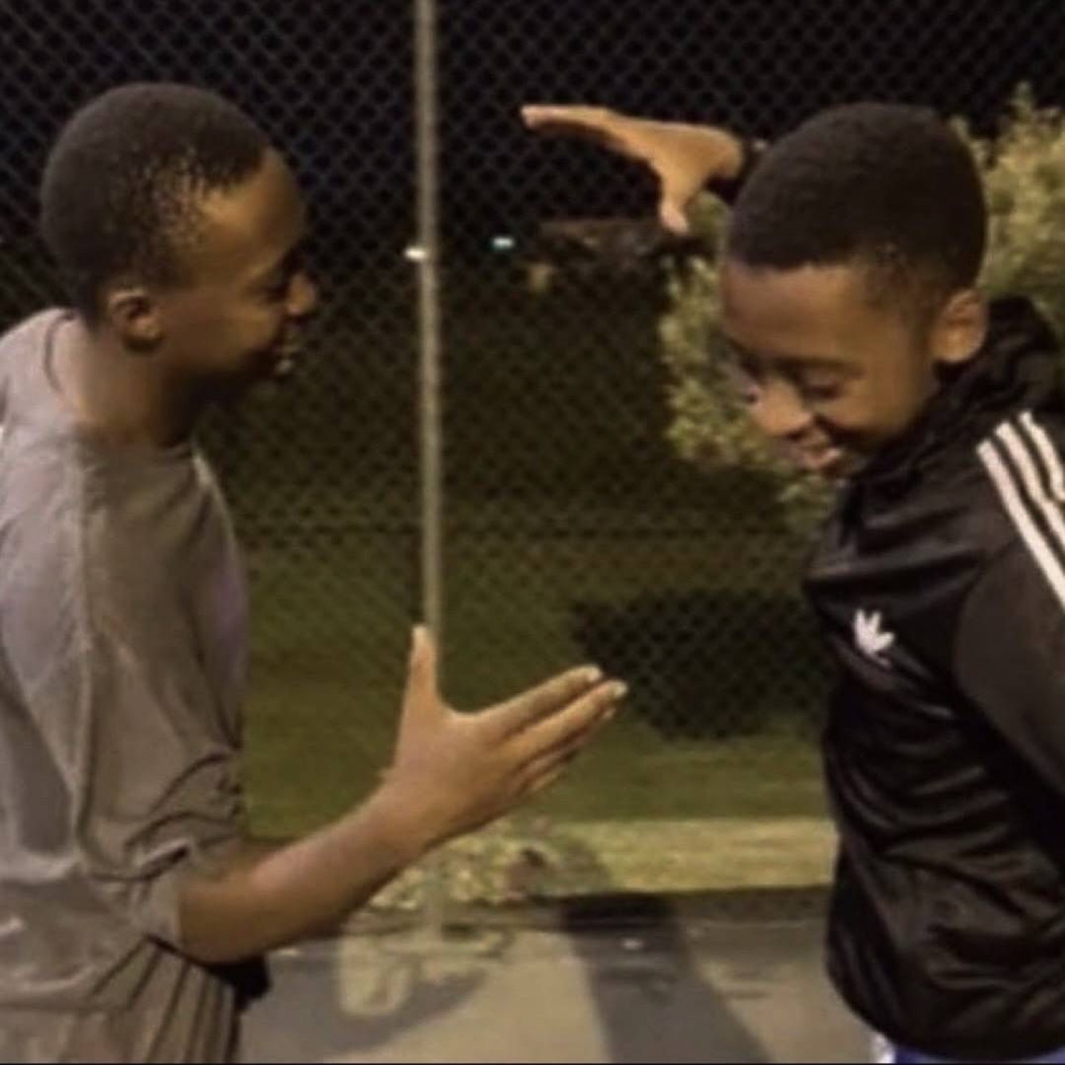 Two guys laughing as they go for a high-five outside at night