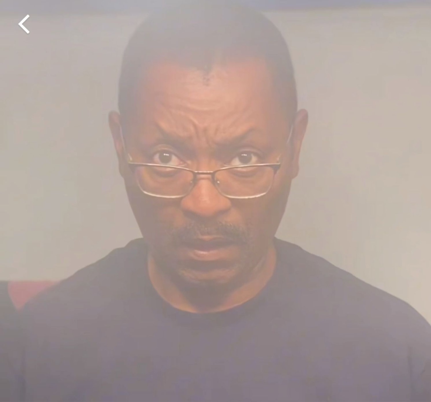Man in glasses staring down at the camera with a stern, unimpressed look