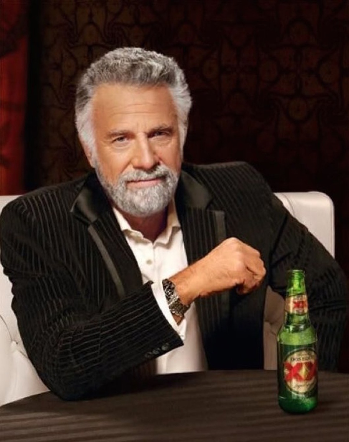 The Most Interesting Man in the World leaning back with a knowing smirk and a Dos Equis