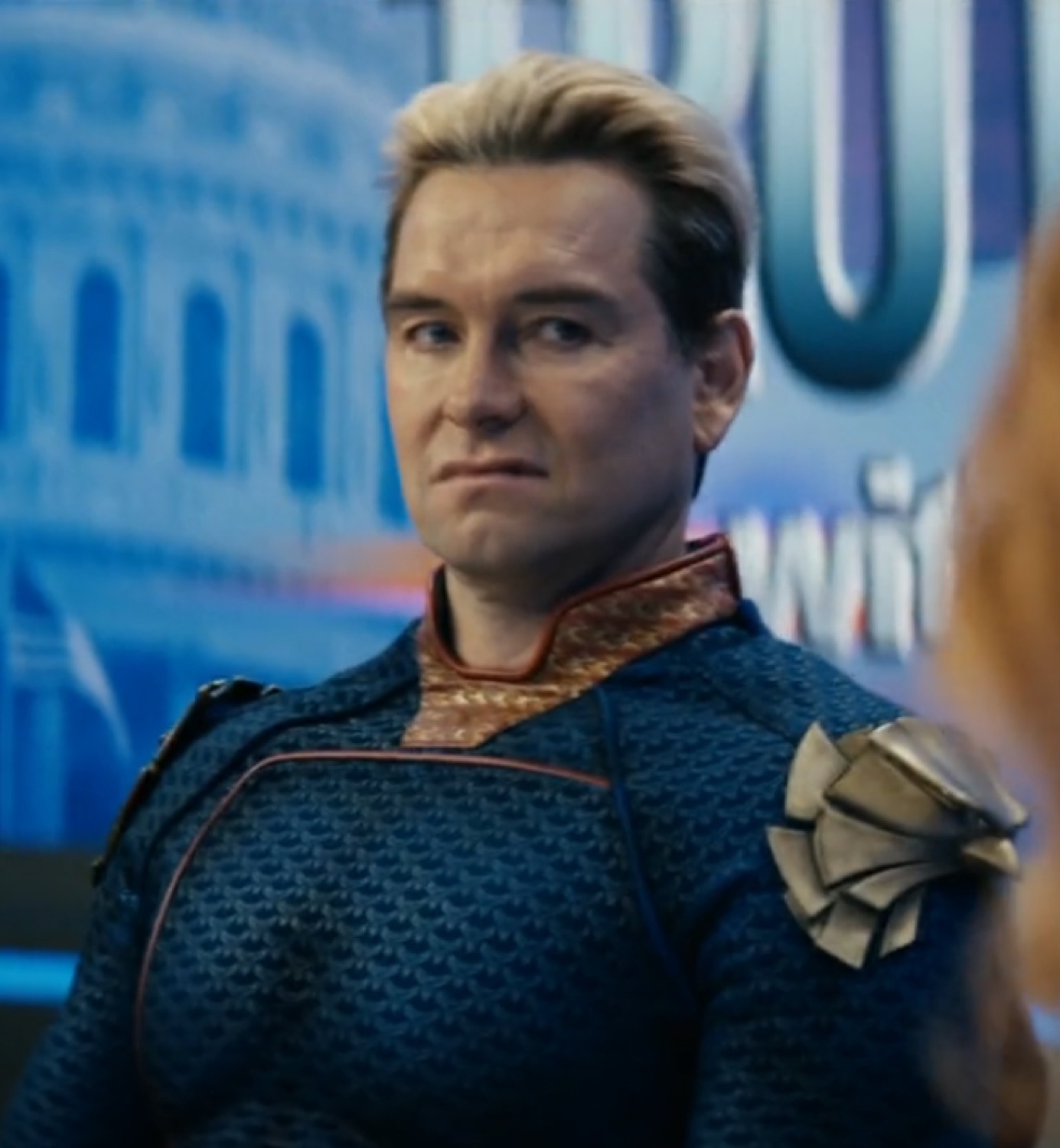 Homelander in his blue suit giving a tight-lipped smug look with obvious contempt