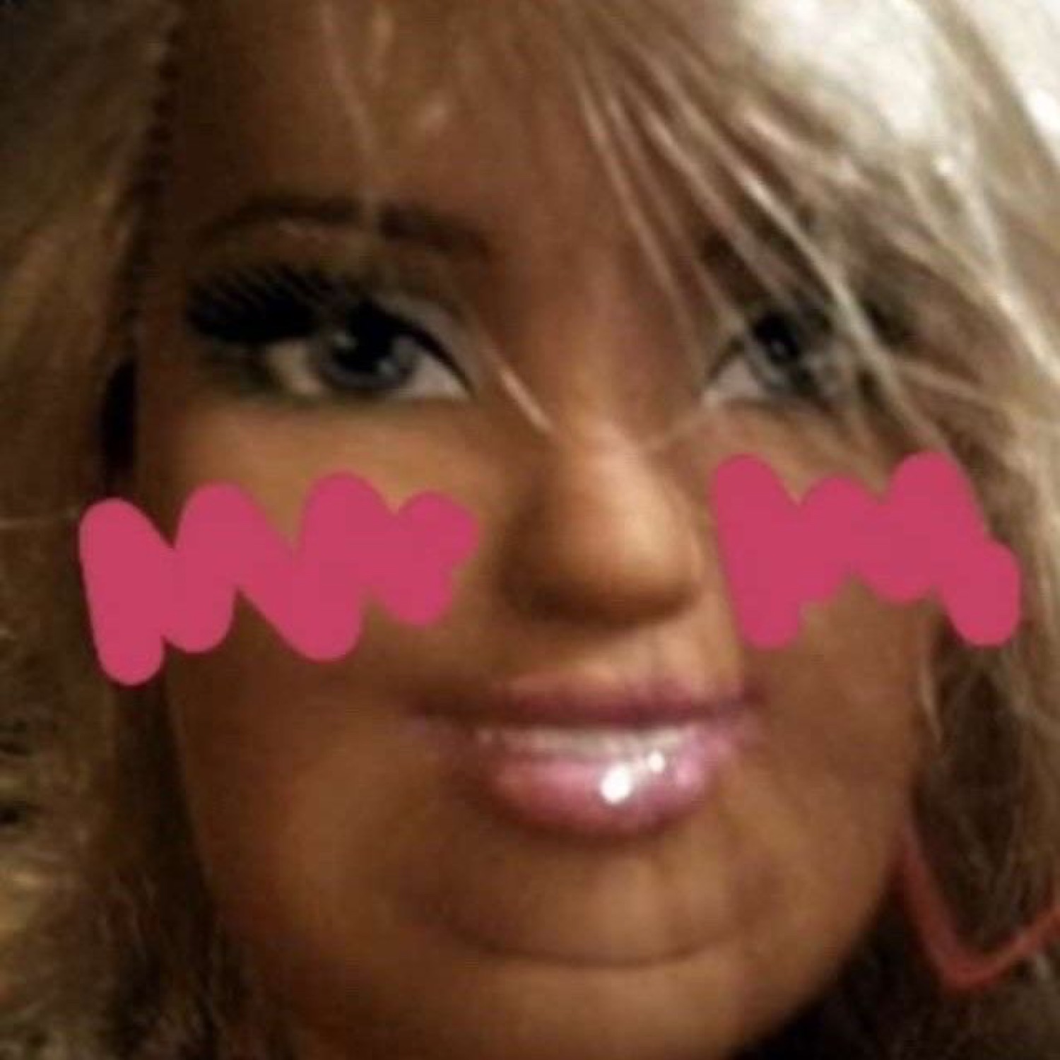 Close-up of a blonde doll's face with pink blush scribbled on both cheeks