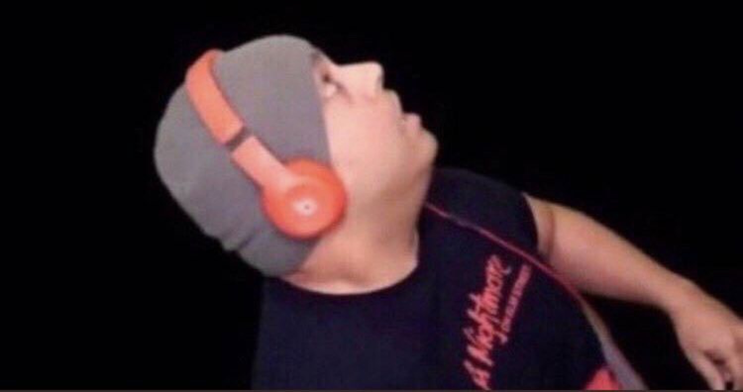 Kid in a beanie and orange headphones throwing his head back, lost in the music