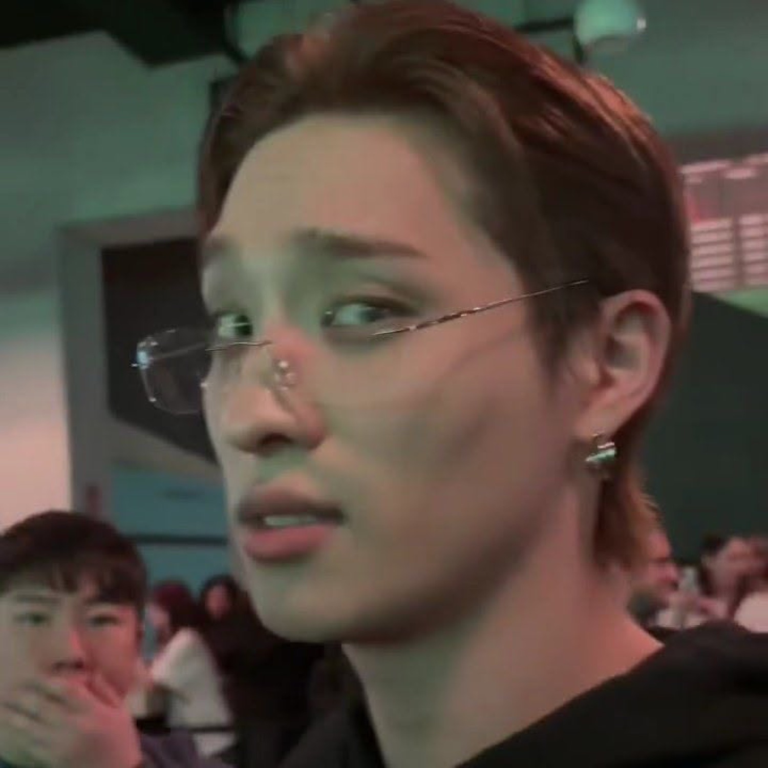 Young person with wire-rimmed glasses and a surprised, unsettled sideways glance