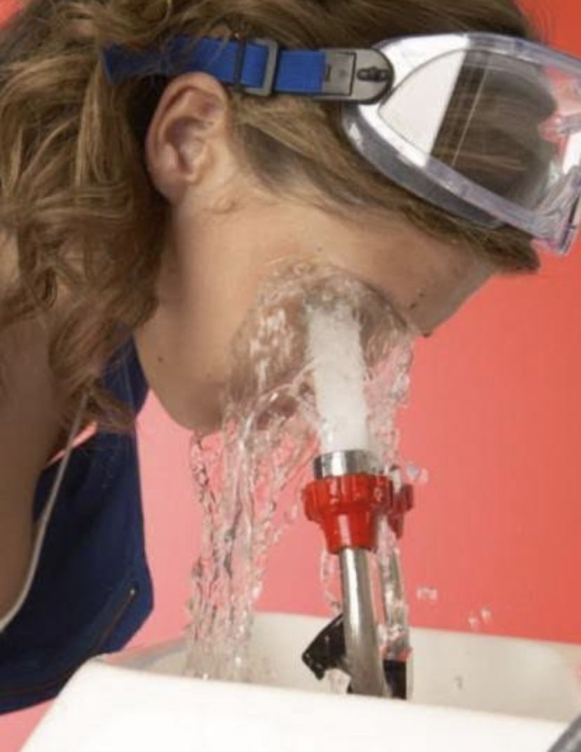 Woman in goggles getting blasted by an eyewash station