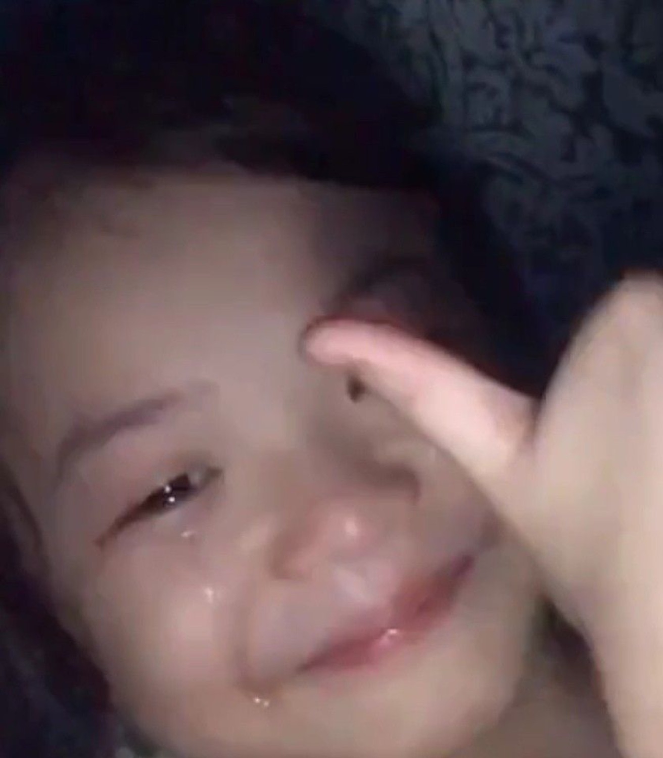 Girl crying and smiling simultaneously while pointing at her own tear-streaked face