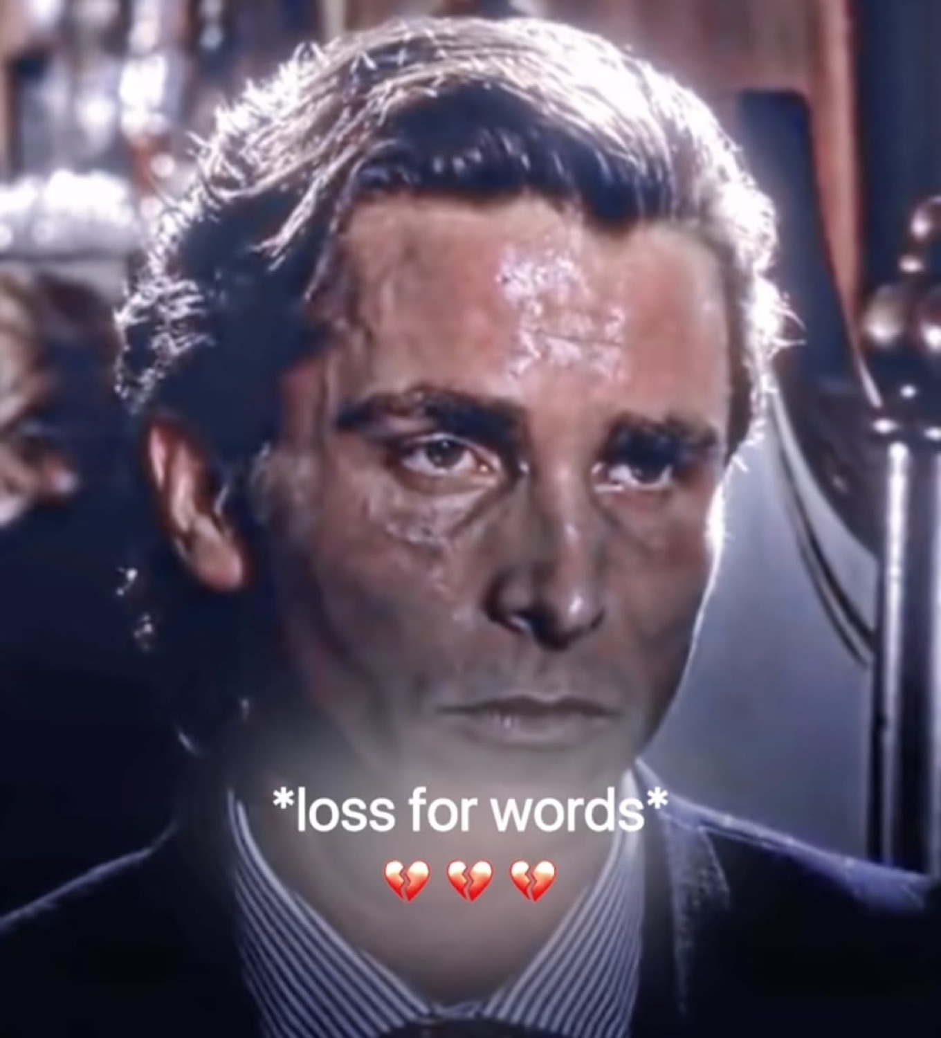 Teary Patrick Bateman gazing forward, captioned '*loss for words*' with broken hearts